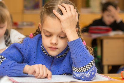 First-grader at a lesson reads the text, running his finger along the lines