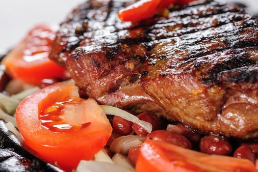 Juicy beef steak with red beans garnish and sliced tomato