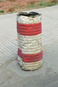 Old iron barrel painted red and white for reporting work on a road in Kenya