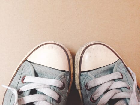 Dirty shoes top view of blue sneakers display on brown background. Vintage effect.