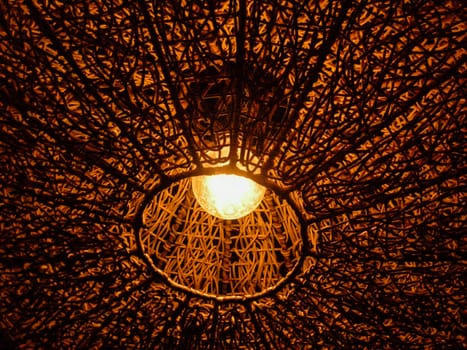 Lamps hanging from the ceiling is made of wood, woven together in a circle.