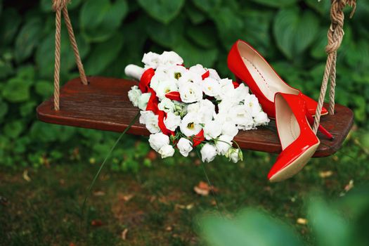 Attributes runaway bride. Wedding bouquet of white roses and red ribbons and red patent leather high-heeled shoes