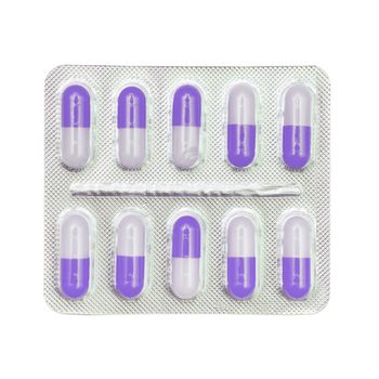 Blister pack of violet and white capsules isolated on white background.