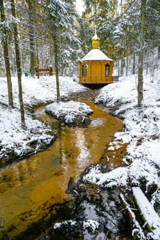 Winter landscape with small river near alcove in a forest