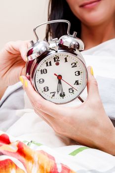 Woman in a bed setting the alarm clock