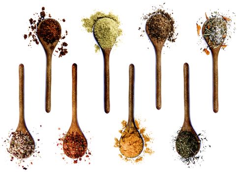 Collection of Various Spices in Wooden Spoons: Dried Paprika, Cumin Powder, Salt with Petals, with Chili and with Cayenne Pepper, Curry Powder and Thyme isolated on White background