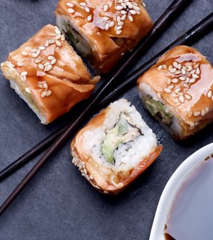 Delicious Smoked Eel Sushi with Soy Sauce and Chopsticks closeup on Black Stone Plate