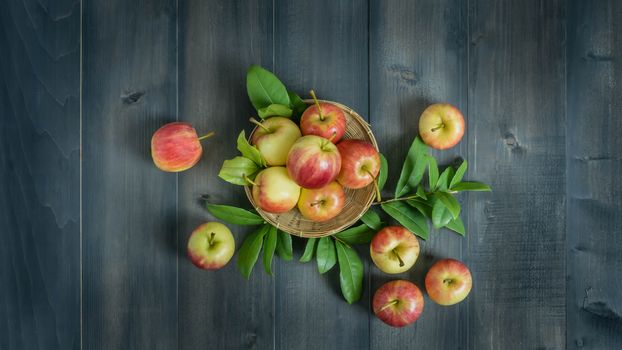 Top view red and yellow apple with leaves and  bamboo basket on wooden background with free space for text
