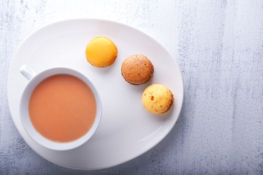 Cup of tea with milk  and french macaroons 
