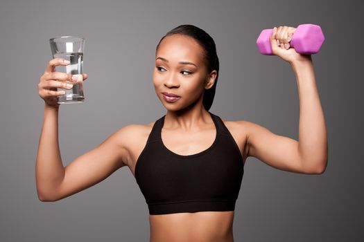 Beautiful healthy black asian woman with glass of water and dumbbell weight workout.