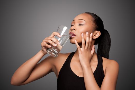 Beautiful healthy black asian woman enjoying drinking glass of water.