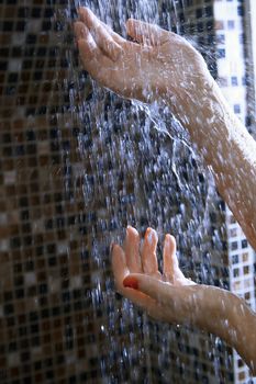 Hands of woman in shower under the flowing water