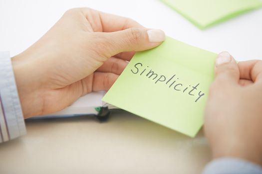 Hands holding sticky note with Simplicity text