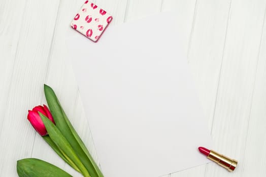 one red tulip and sheet of paper for your greetings on the background of white wooden board