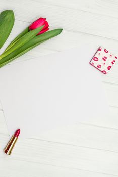 one red tulip and sheet of paper for your greetings on the background of white wooden board