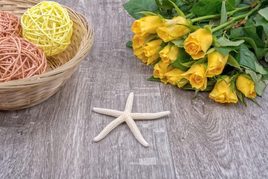 White starfishes and yellow roses on a wooden background