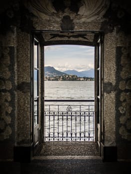 View of lake in the Italian Alps from inside old palace, through an open door over a balcony