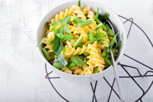 Pasta salad with asparagus and arugula on a white plate