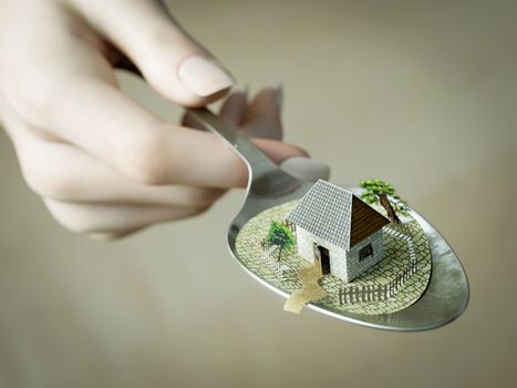 woman hand holding spoon with paper house real estate business concept photo