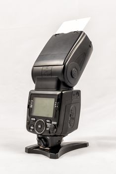 Back view of a black unbranded external flash unit for DSLR camera with bounce card extended