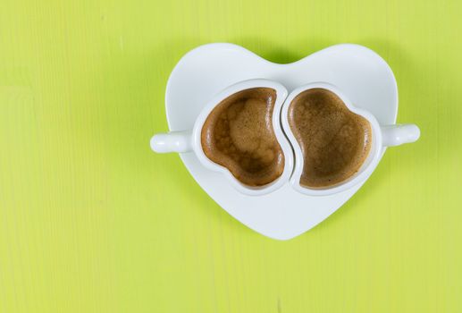 Flat lay with two cups of espresso coffee on a green wooden board. Concept for romance