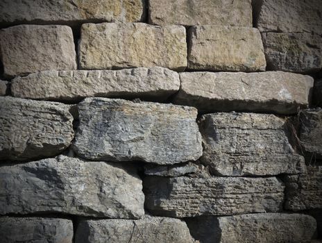 stone wall background with grey and golden stones and dark edges