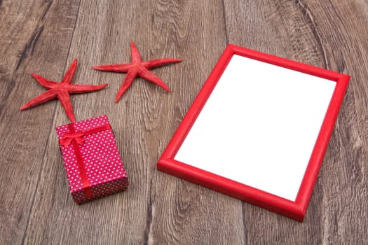 Red starfishes, gift and picture frame on a wooden background