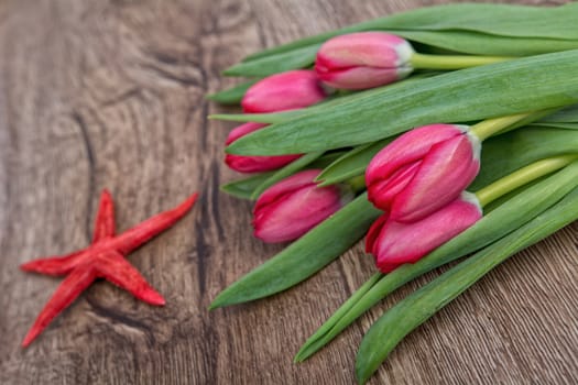 Starfish and red tulips on a wooden background