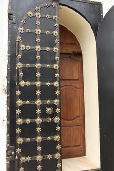 Ancient solid double doors open, decorated gold flowers
