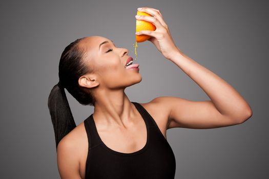 Beautiful healthy happy black asian woman squeezing delicious orange juice mandarin fruit.
