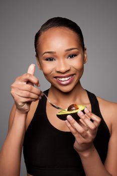 Beautiful healthy happy black asian woman holding delicious avocado super fruit with spoon.
