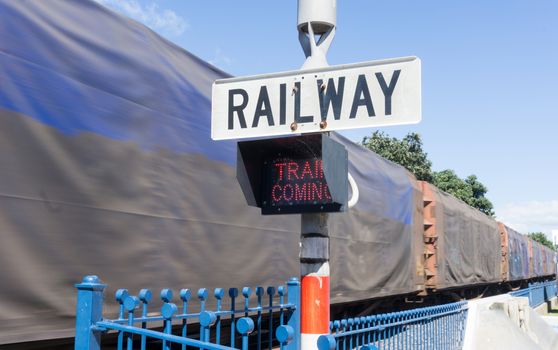 Railway sign and passing cargo train in downtown Tauranga New Zealand.