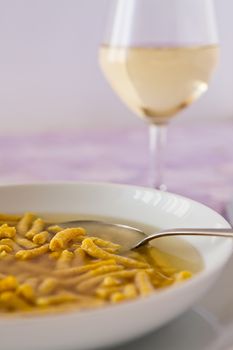 Passatelli in broth original Italian pasta  and a glass of white wine