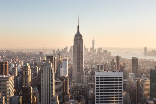 New York City. Manhattan downtown skyline with illuminated Empire State Building and skyscrapers at sunset.