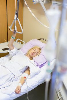 Bedridden female patient lying in hospital bed, recovering after surgery.