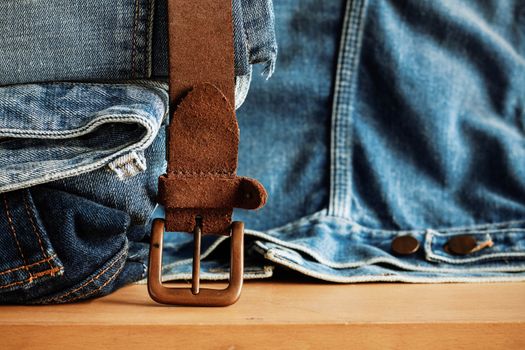 Old leather belt with jeans on a wooden floor.