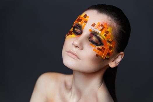 Portrait of a girl with an original make-up. Beauty close-up. Orange and red rhinestones on a face