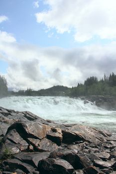 Waterfall and river in green forest in northern Norway at summer