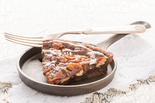 Slice of chocolate pecan pie photographed from a closeup angle.