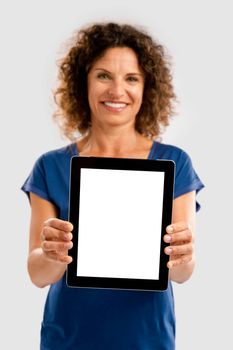 Beautiful middle aged woman holding and showing something on a tablet