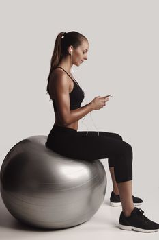 Shot of a beautiful young woman setting the music playlist for the workout.