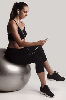 Shot of a beautiful young woman setting the music playlist for the workout.