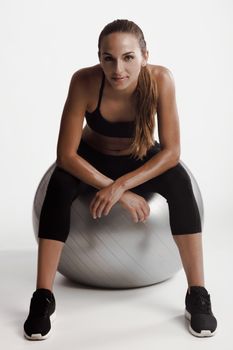 Shot of a beautiful young woman sitting on swiss ball after the train