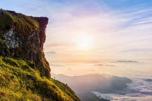 Beautiful landscape nature of sunrise on peak mountain with sun cloud fog and bright colors of sky in winter at Phu Chi Fa Forest Park is a famous tourist attraction of Chiang Rai Province, Thailand