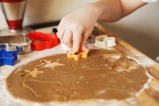 Children's hands make gingerbread. Small boy cutting cookies for Christmas. Kid Baking Cooking Cookies Fun Concept. Master class for children on baking christmas gingerbread.