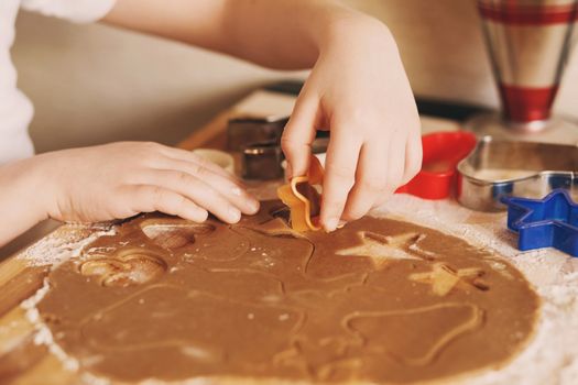 Children's hands make gingerbread. Small boy cutting cookies for Christmas. Kid Baking Cooking Cookies Fun Concept. Master class for children on baking christmas gingerbread.