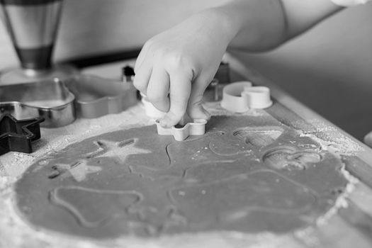 Children's hands make gingerbread. Small boy cutting cookies for Christmas. Kid Baking Cooking Cookies Fun Concept. Master class for children on baking christmas gingerbread.