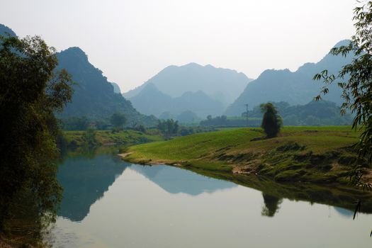 Beautiful countryside of Quang Binh, Viet Nam on day with green agriculture field near river, mountains chain reflect oh water, fresh air, eco green make nice destination when travel to Vietnam