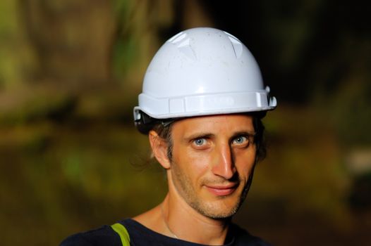 a portrait of a worker with white helmet on head, on nature background