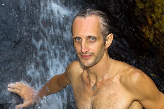a man taking a relaxing shower under a waterfall outside